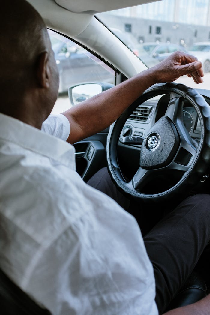 services-01 A man driving a vehicle, highlighting the steering wheel and car interior.