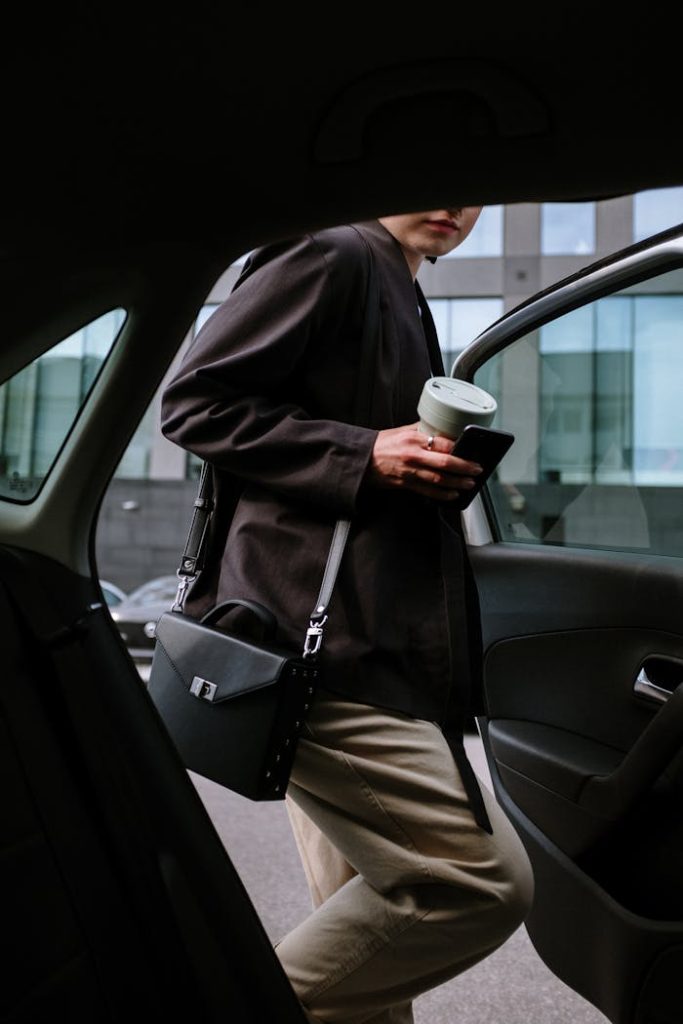 pexels photo 4606397 Stylish woman entering a car, holding coffee and smartphone, showcasing urban lifestyle.